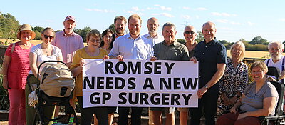 Thomas Gravatt and the local Lib Dems with a banner that says 'Romsey needs a new GP Surgery'